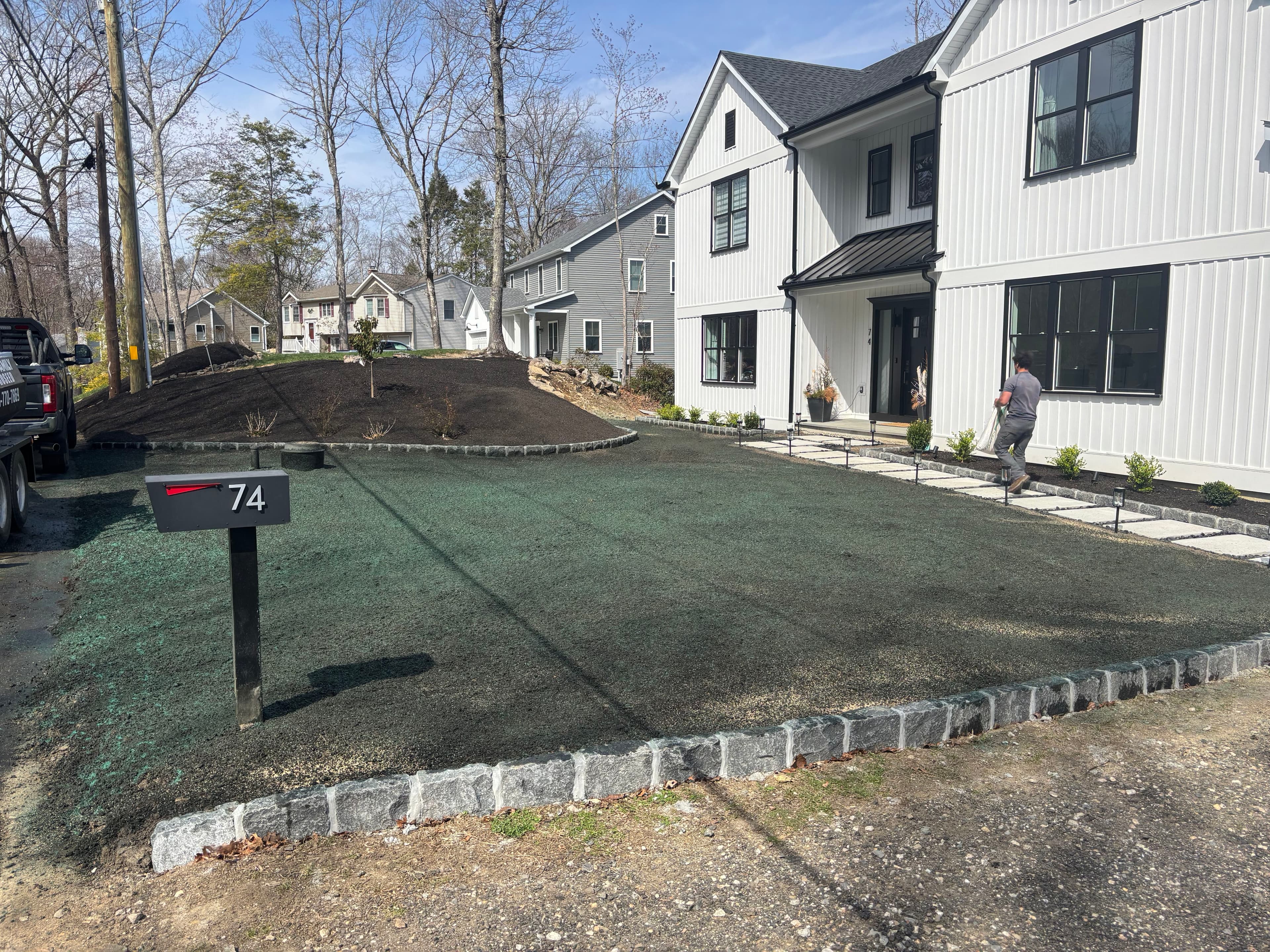 Newly landscaped front yard with sod, stones, and modern home design .